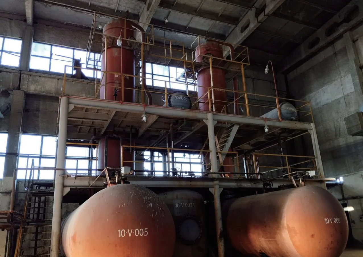 Red industrial vessels, tanks and elevated pipework inside a Reftech facility
